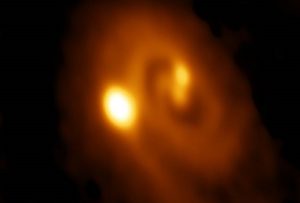 ALMA-opname op een golflengte van 1,3 mm van de drievoudige protoster L1448 IRS3B. De opname laat de spiraalstructuur en de emissie naar de drie protosterren zien. De helderste emissie is richting het buitenste en jongste lid van het trio. De opname beslaat 3,5 boogseconden, wat overeenkomt met circa 800 astronomische eenheden oftewel achtmaal de grootte van ons zonnestelsel. 