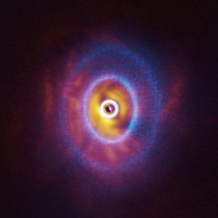 Nieuwe waarnemingen tonen planeet-vormende schijf die door zijn drie centrale sterren uit elkaar getrokken is